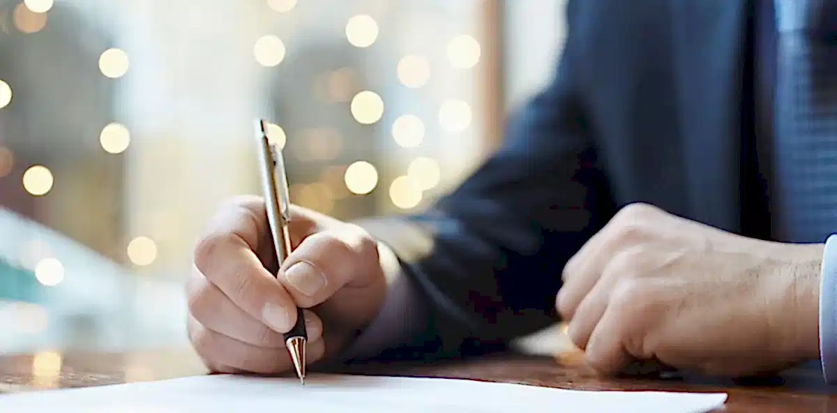 Closeup of a person's hand signing a document.