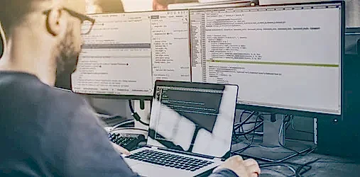 A man working on several screens.