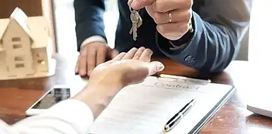 Real estate professional handing keys to home owner.