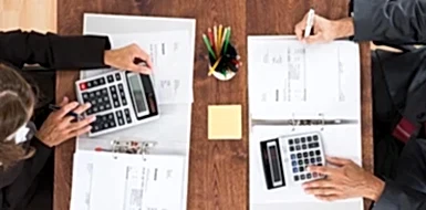 Two accountants calculate budget using calculators.