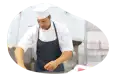 A butcher in an apron cutting up meat.