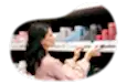 Candle shop employee placing pricing on a store shelf holding candles.