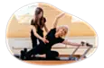 Pilates instructor assisting a client with their form in a fitness center.