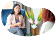 Psychologist sitting in a chair speaking with a patient in an office.