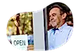 A small business owner hanging the "open" sign at their new store location